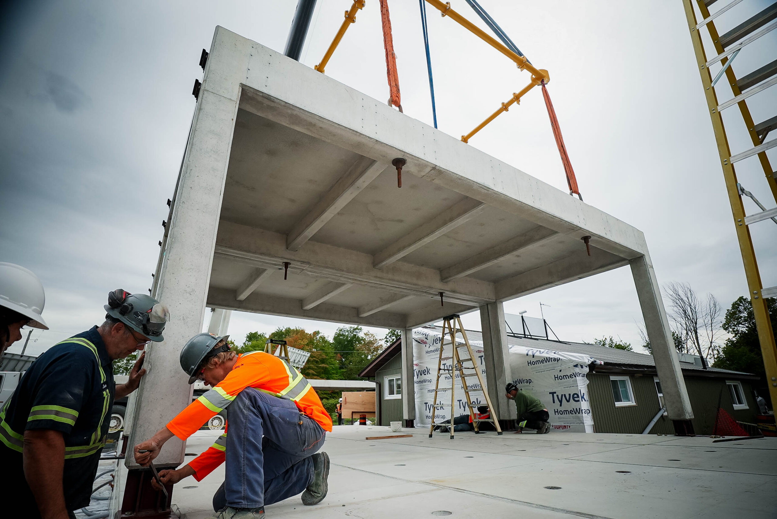 Crew guiding a precast module into position on prepared connection points.