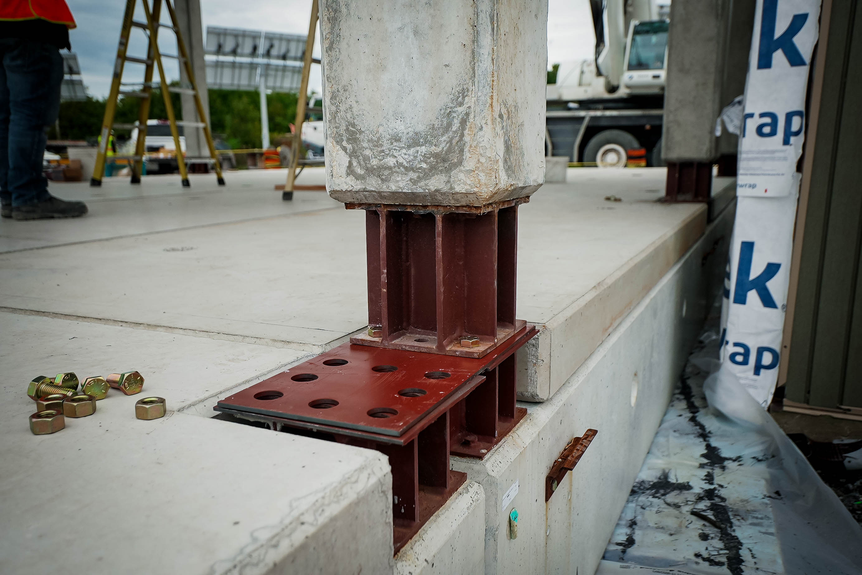 Bolted steel interface at a precast column and adjacent concrete elements during installation.
