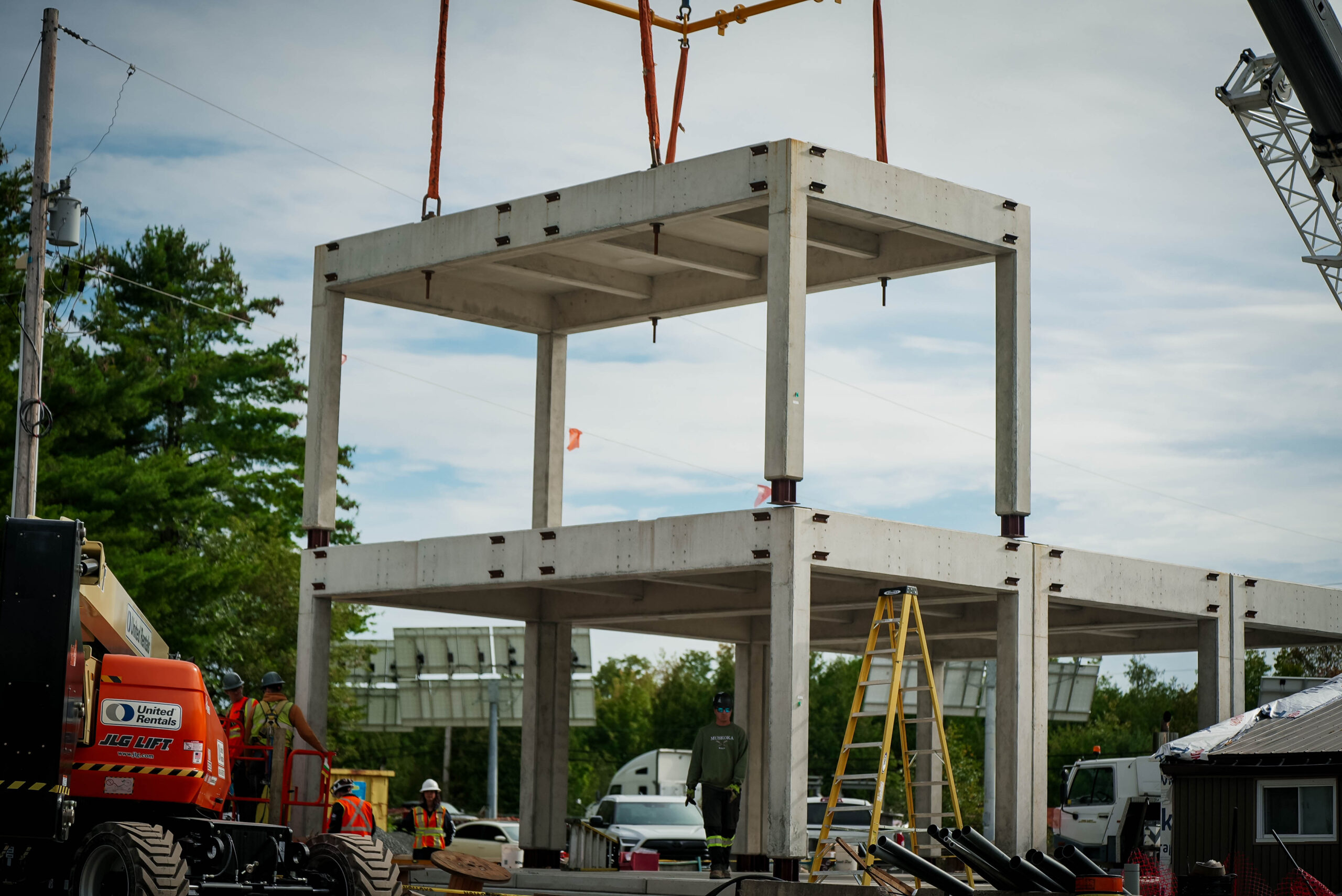 Precast modules being aligned and stacked into a two-level structural frame.